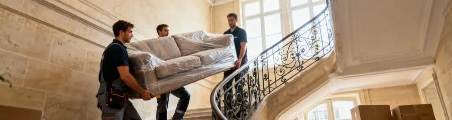 Déménageurs transportant canapé escaliers immeuble haussmannien, manutention verticale coordonnée Lyon