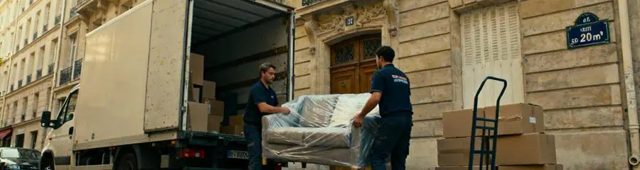 Camion déménagement rue parisienne étroite, déchargement devant immeuble haussmannien typique