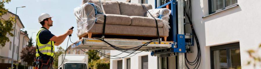 Technicien opérant monte-meuble transportant canapé vers étage, location professionnelle sécurisée