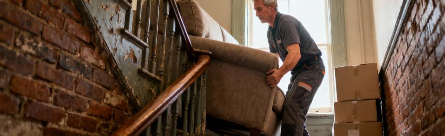Déménageur manœuvrant canapé dans escalier étroit maison ancienne nordiste, passage technique difficile