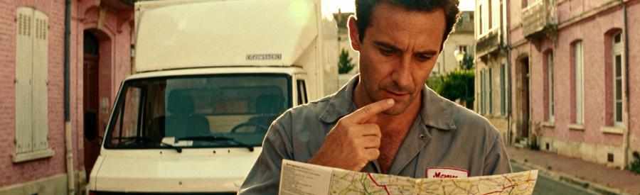 Déménageur professionnel consultant itinéraire devant camion, architecture Montauban arrière-plan