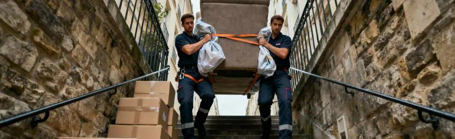 Déménageurs transportant canapé dans escalier étroit d'immeuble ancien à Montreuil avec équipement professionnel