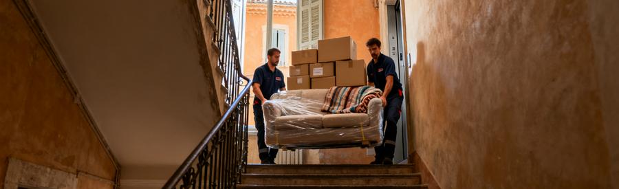 Déménageurs transportant meubles dans escalier étroit d'immeuble provençal sans ascenseur