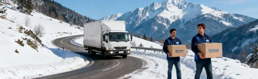 Camion de déménagement manœuvrant sur une route montagneuse enneigée dans les Vosges avec déménageurs portant des cartons.